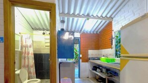 A compact kitchen with a toilet and a shower area.