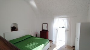 Una camera da letto con un letto, una cassettiera, uno specchio e una porta.