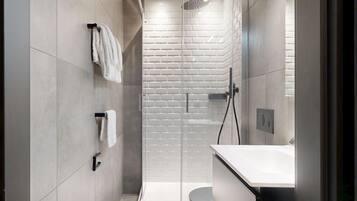 Une salle de bain moderne avec une douche à parois de verre, un lavabo blanc et des toilettes.