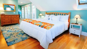 A bedroom with a large bed, a wooden dresser, a nightstand, and a window with blinds. - Penthouse Unit in Provincetown Center (Provincetown)