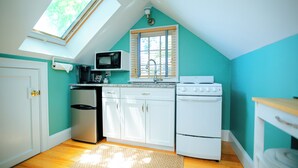 A kitchen with a skylight, white cabinets, a microwave, a sink, and a stove. - Penthouse Unit in Provincetown Center (Provincetown)