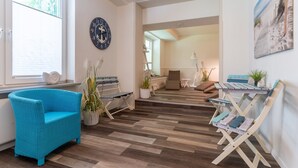 Een moderne woonkamer met een blauwe fauteuil, een houten salontafel en uitzicht op de aangrenzende eetruimte.