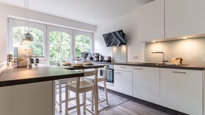 Een moderne keuken met witte kasten, een groot raam en een inbouwoven.