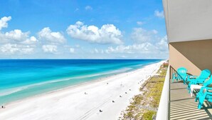 A beach view from a balcony with turquoise chairs and a clear blue sky. - Grandview East 1002 (Panama City Beach)