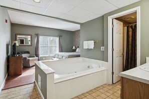 A bathroom with a bathtub, a sink, a mirror, and a window.