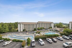 A multi-story hotel with a swimming pool and a parking lot.