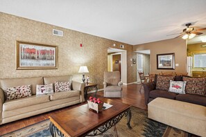 A living room with a beige sofa, a wooden coffee table, and a fireplace.
