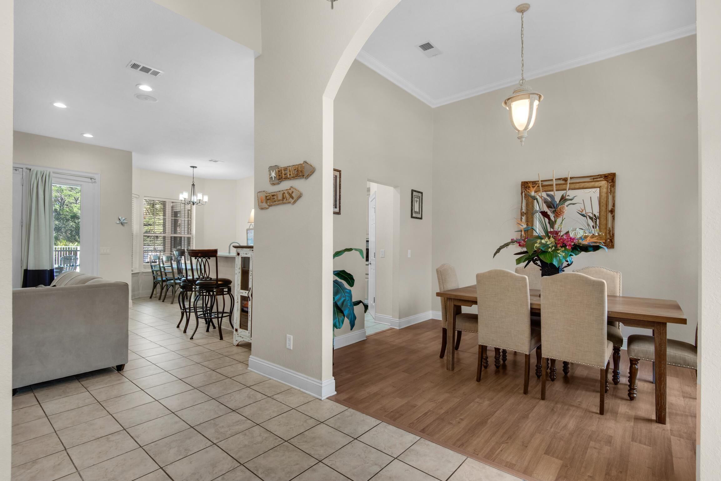 A spacious living area with a dining table and chairs, a sofa, and a chandelier.