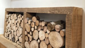 A wooden log display with a mountain landscape painting above. - Cosy 2 bed barn in Bannau Brycheiniog national park, with outdoor patio.  (Brecon, Powys)