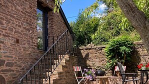 A stone building with a staircase leading to a covered area with outdoor seating. - Cosy 2 bed barn in Bannau Brycheiniog national park, with outdoor patio.  (Brecon, Powys)