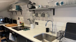 A modern kitchen with a stainless steel sink, a kettle, and various kitchen utensils on the countertop. - Cosy 2 bed barn in Bannau Brycheiniog national park, with outdoor patio.  (Brecon, Powys)