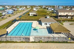 Une piscine avec des couloirs de nage, un poste de surveillance pour les sauveteurs et un pavillon à toit de chaume.