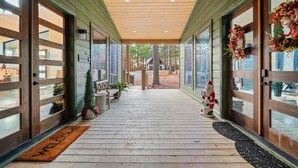 Eine überdachte Veranda mit Holzboden, großen Glasfenstertüren und einer Fußmatte.