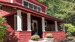 A red wooden house with a porch, stone steps, and a mailbox. - Cozy Adirondack Escape (Warrensburg)