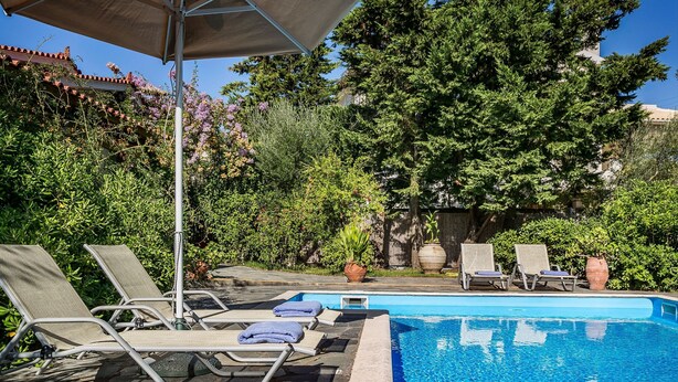 En swimmingpool med liggestole og en pergola.