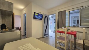 Une chambre d’hôtel comprenant un lit, un bureau avec une chaise, une télévision et une porte donnant sur une salle de bain.