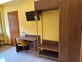 A room with a bunk bed, a desk, a chair, and a television mounted on the wall.