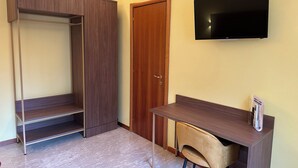 Une chambre équipée d’une armoire, d’un bureau, d’une chaise et d’un téléviseur à écran plat fixé au mur.