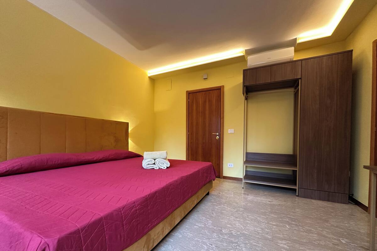 Ein Hotelzimmer mit Bett, Holz-Kopfteil, Schrank und eingebauter Sitzbank.