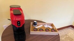 Une machine à café et un plateau avec des dosettes de café, le tout posé sur une table ronde en bois.