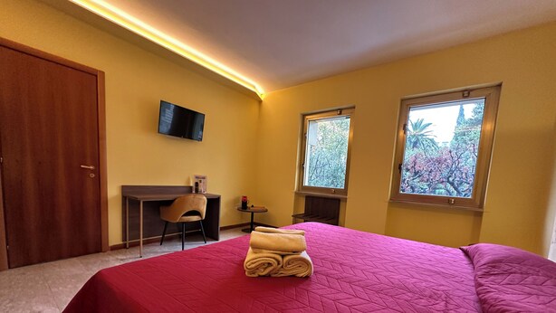 Une chambre d ’hôtel avec un lit, un bureau, une chaise et deux fenêtres.