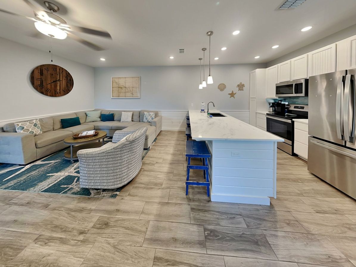 A modern kitchen with a central island, built-in appliances, and a seating area with a sofa and chairs.