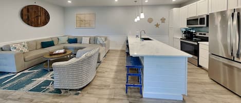 A modern kitchen with a central island, built-in appliances, and a seating area with a sofa and chairs.