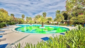 A swimming pool with lounge chairs and palm trees. - Residence with swimming pool in Ottiolu (Budoni)