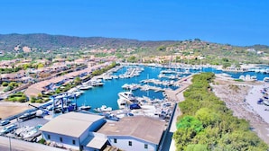 A marina with numerous boats docked, surrounded by residential buildings and greenery. - Residence with swimming pool in Ottiolu (Budoni)