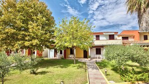 A courtyard with a paved walkway, a small seating area, and a building with a tiled roof. - Residence with swimming pool in Ottiolu (Budoni)