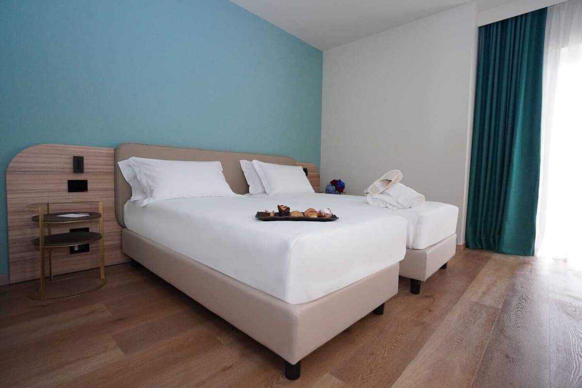 Ein Hotelzimmer mit einem großen Bett, einem Nachttisch, einem kleinen Tisch und einem Stuhl.