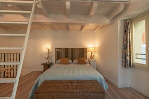 A bedroom with a bed, nightstands, a lamp, a window with curtains, a wooden ladder, and a wooden bench. - Casa di Tully in Sarnico (Sarnico)