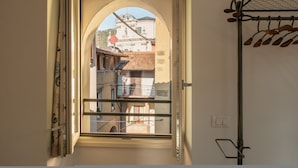 A room with a window overlooking a street, a metal rack with clothes, and a wall switch. - Casa di Tully in Sarnico (Sarnico)