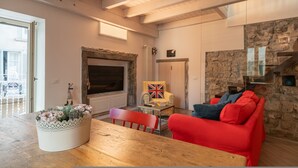 A cozy living room with a stone wall, a fireplace, a red sofa, and a wooden table. - Casa di Tully in Sarnico (Sarnico)