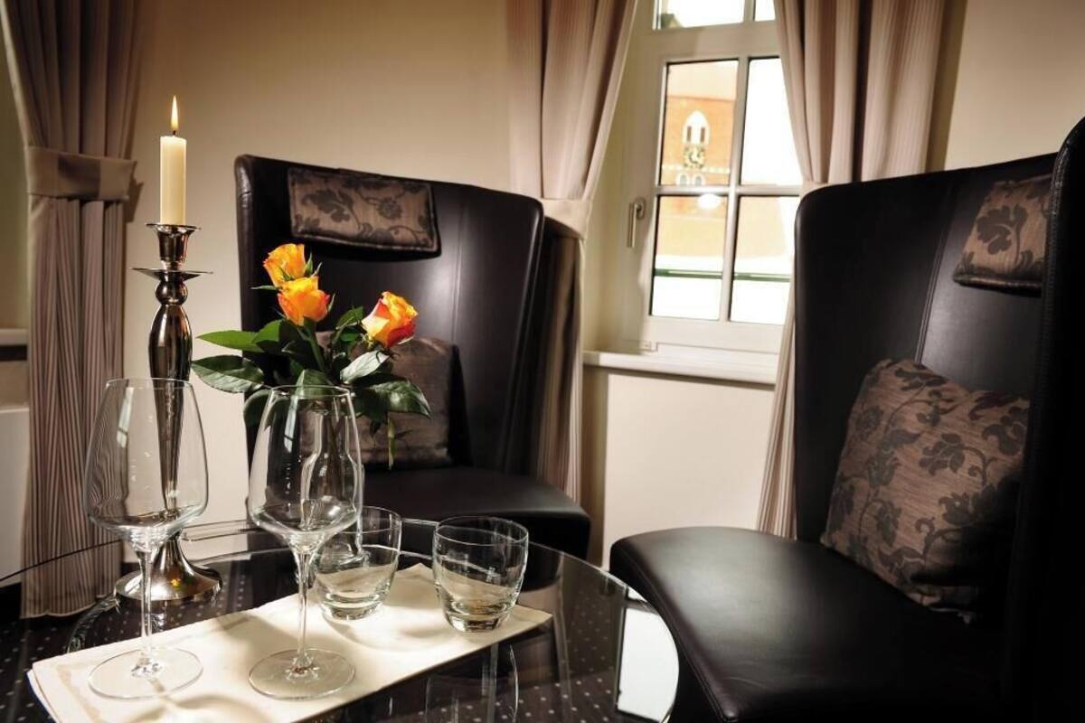 Una habitación con una mesa preparada para dos personas, con una vela, un florero con flores y copas de vino.