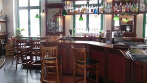 Un'area bar con sedie di legno, un bancone e scaffali pieni di bottiglie.