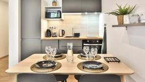 A modern kitchen with a dining table set for four, equipped with a microwave, kettle, and coffee maker.