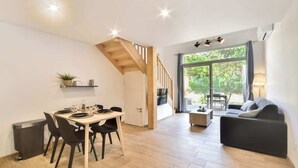 A modern living space with a dining area, a staircase, and a sofa.