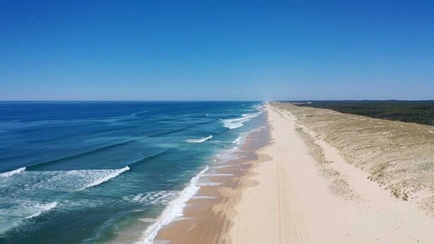 A beach with a long stretch of sand and ocean waves.