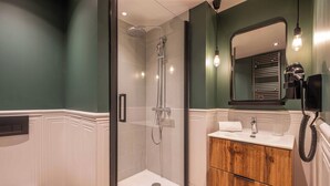 Baño con ducha, inodoro, tocador y espejo.