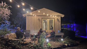 Puuinen mökki, jossa on kuisti, koristeelliset valonauhat ja ulkotila istumiseen.