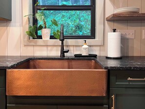 Enjoy a kitchen with a large sink, window views of lush greenery, and a sleek countertop.