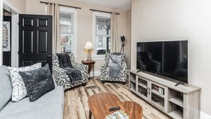 A living room with a sofa, two patterned armchairs, a coffee table, a TV, and a cabinet. - Stylish Family Retreat | Near Downtown & Street Parking (Pittsburgh)