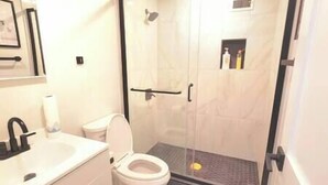 A bathroom with a toilet, sink, and shower area.