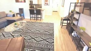 A living room with a patterned rug, a sofa, a coffee table, and a bookshelf.