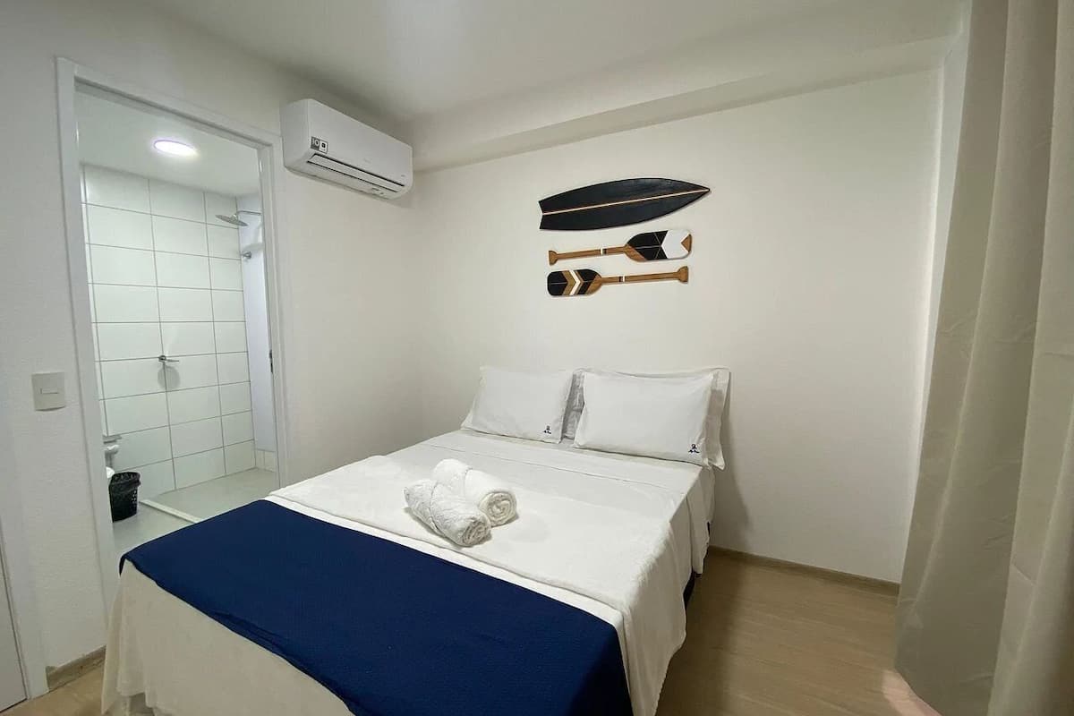 A hotel room with a bed, a shower, and a wall-mounted paddleboard.