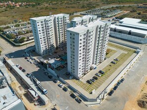 Een hoog appartementencomplex met meerdere verdiepingen, parkeerplaatsen en een zwembad.