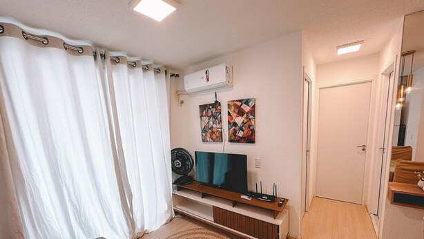 A living room with a sofa, TV, and air conditioning unit. - Mirante Clube - Praia do Futuro (Fortaleza)