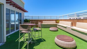 A rooftop terrace with a seating area, a table, and a sofa. - Mirante Clube - Praia do Futuro (Fortaleza)
