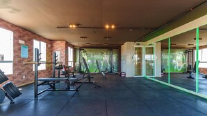 Een sportschool met gewichthefapparatuur, spiegelwanden en een bakstenen muur.